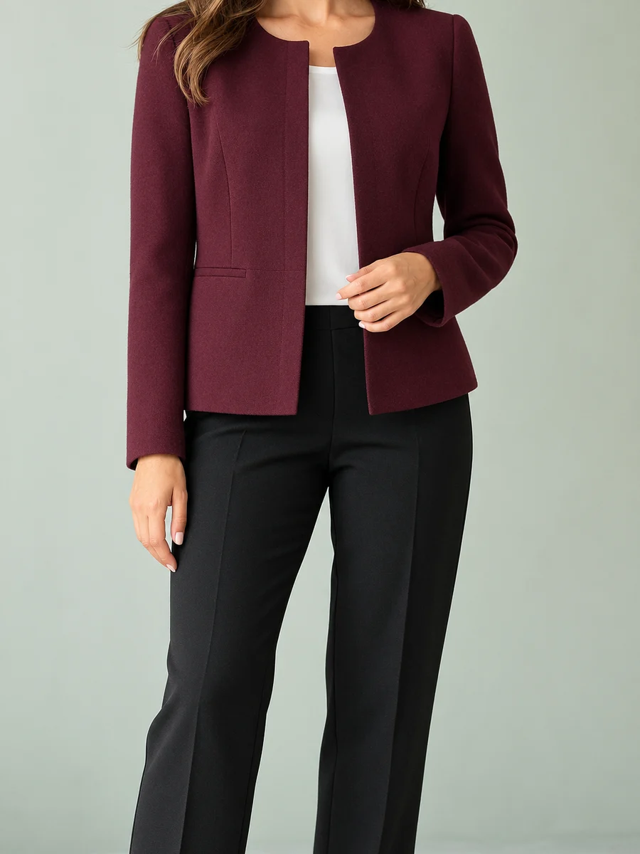 Mujer con chaqueta burdeos sin solapas, de corte recto y bolsillos con cartera, sobre top blanco y pantalón negro